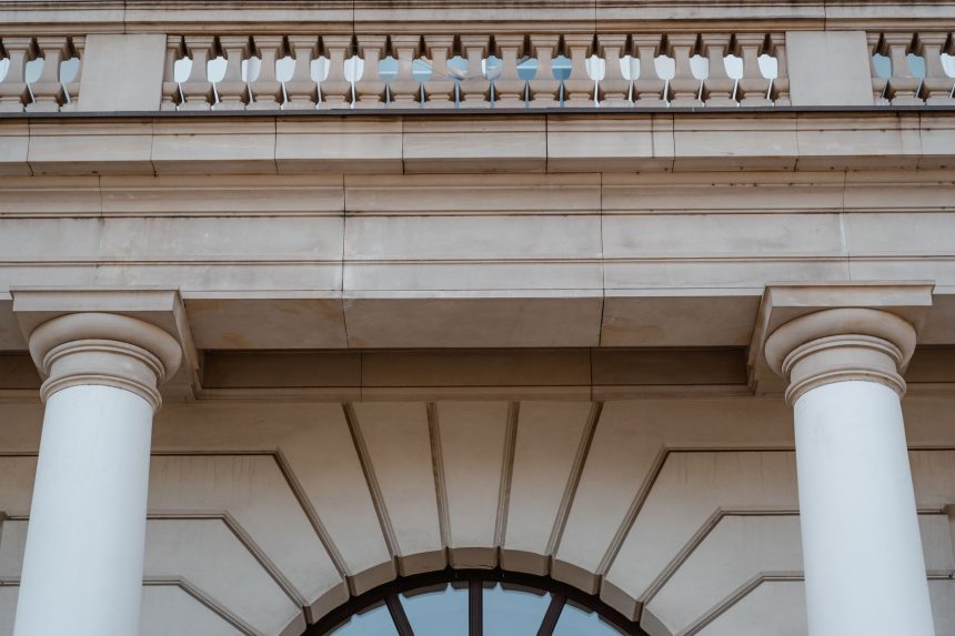 Fachada de prédio público neoclássico com colunas e sacada, vista durante o dia