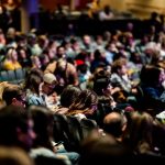 Público diversificado sentado em um auditório durante um evento interno