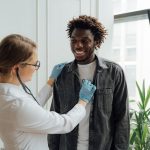 Médico examina uma paciente sorridente em uma clínica de saúde.