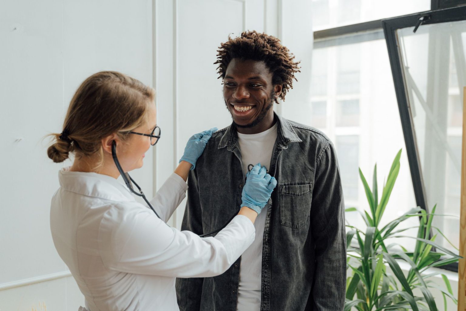 Médico examina uma paciente sorridente em uma clínica de saúde.
