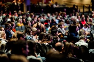 Público diversificado sentado em um auditório durante um evento interno