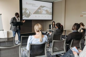 Participantes acompanham uma apresentação sobre negócios em uma sala de conferências.