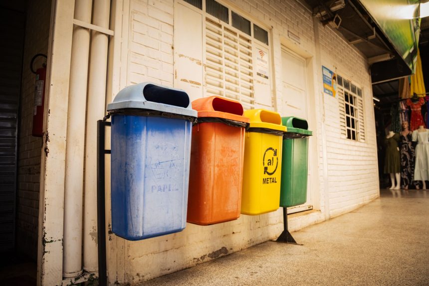 Quatro lixeiras para diferentes tipos de materiais dispostas em um espaço urbano, destacando a separação de resíduos.