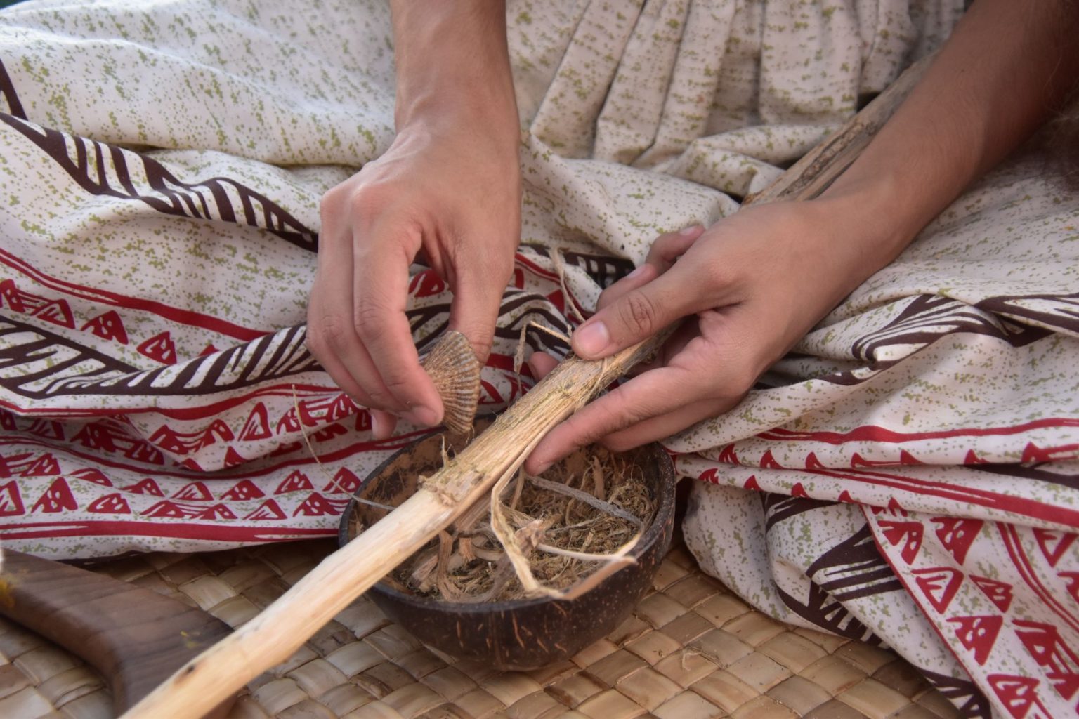 Mãos de artesão trabalhando com madeira e fibras naturais em um ambiente tradicional.