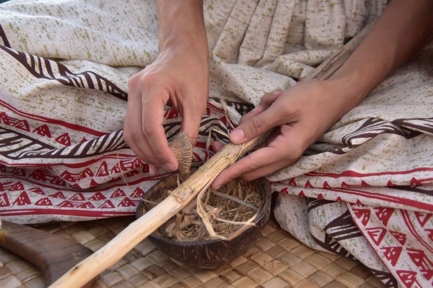 Mãos de artesão trabalhando com madeira e fibras naturais em um ambiente tradicional.