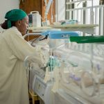 Profissional de saúde atende recém-nascidos em incubadoras em uma unidade neonatal hospitalar.