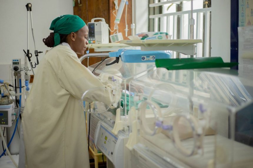Profissional de saúde atende recém-nascidos em incubadoras em uma unidade neonatal hospitalar.