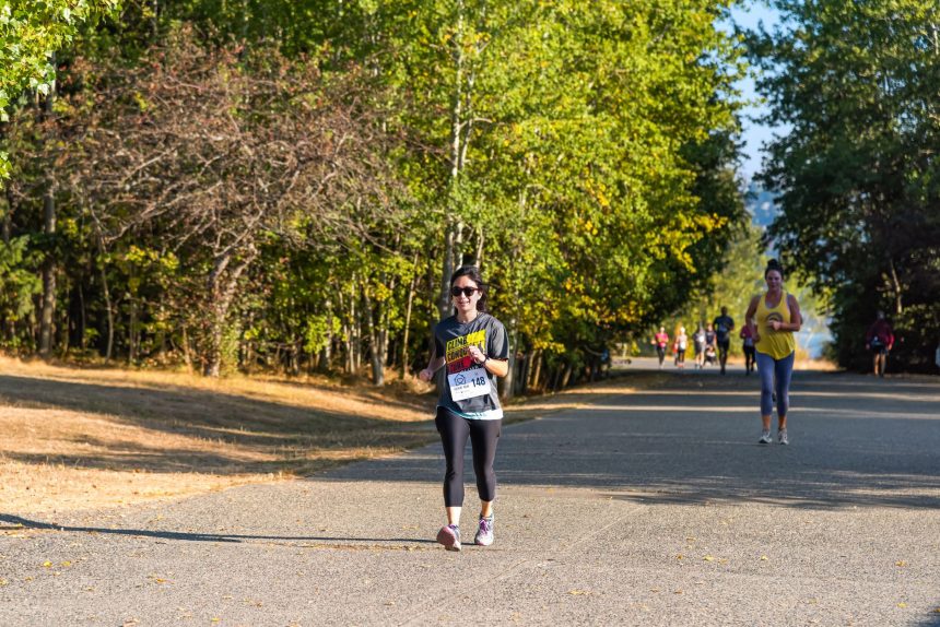 Grupo de mulheres correndo em uma estrada arborizada durante uma prova esportiva.